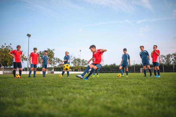 istock Red and Blue Jersey Footballers Lined Up for Practice Kicks 1220731691