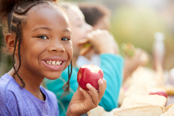 시골의 야외 테이블에서 건강한 피크닉을 먹는 친구와 소녀의 초상화 - apple eating healthy eating friendship 뉴스 사진 이미지