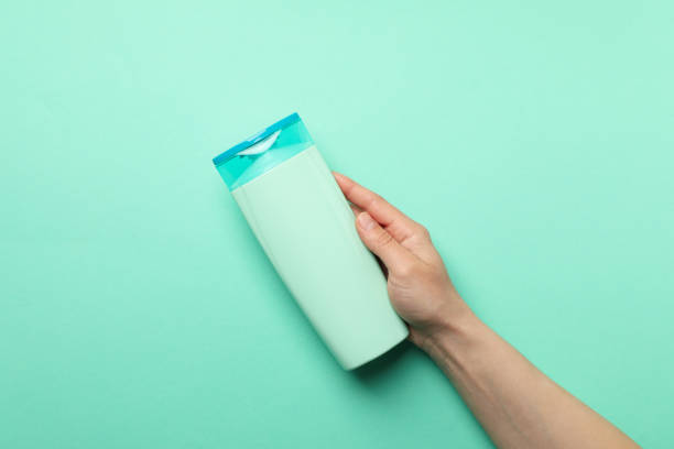 istock Female hand holds shampoo bottle on mint background, space for text 1220731768