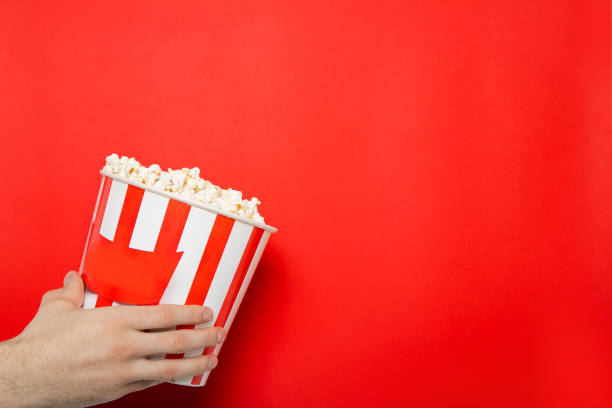 istock The guy holds popcorn in his hands on a red background. Place for text. 1220732929