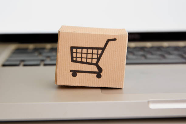 Online shopping . ecommerce and delivery service concept : Paper cartons with a cart or trolley logo on a laptop keyboard, depicts customers order things from retailer sites via the internet compras en línea . concepto de comercio electrónico y servicio de entrega : cartones de papel con un logotipo de carrito o carrito en un teclado portátil, representa a los clientes pedir cosas de los sitios minoristas a través de internet
