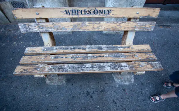 For "whites only" - a bench in Cape town. Bench with the inscription, as the memory of apartheid and segregation in South Africa. Memorial bench and feet of a passing boy