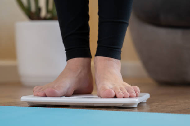 istock Young woman standing on scale, close-up 1220736568