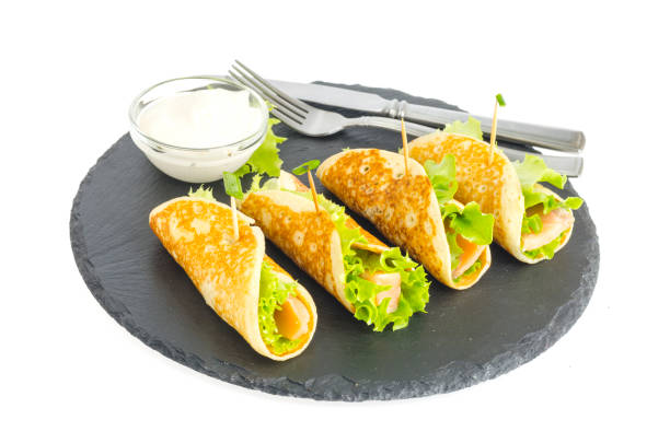istock Pancake rolls with fish and lettuce. Salmon bread roll with cheese. On black stone plate. 1220736980