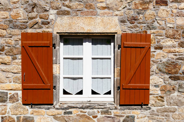 istock Old wooden shutters painted brown on a stone masonry wall 1220738667