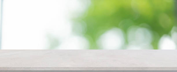 istock abstract blurred garden view form living room window with concrete table background for show , promote ,design banner ads on display concept 1220739163