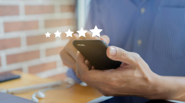 istock close up on customer man hand pressing on smartphone screen with  five star rating feedback icon and press level excellent rank for giving best score point to review the service , technology business concept 1220739167