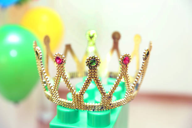 A Genuine Plastic King or Queen crown in Gold Plastic with Colorful Plastic Jewels . selective focus . Girls Plastic Toy Tiara Crown. Room for text.