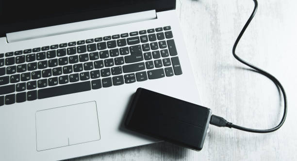 istock external hard drive connected to the laptop computer on table 1220742669