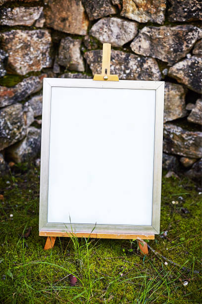 Easel staying om grass and moss near ancient stone walll with copy space stock photo