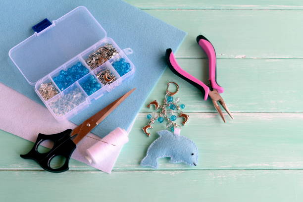 istock Easy felt dolphin keychain. Cute felt keychain diy, bag decoration ideas crafts. A set of tools and materials for children craft activities and sewing projects. Wooden background 1220742999
