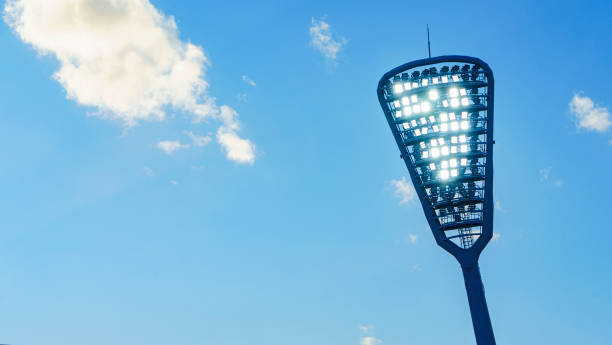 스포트라이트가 있는 마스트가 경기장에 빛을 비추고 있습니다. 클래식 블루 하늘 배경입니다. 텍스트의 공백입니다. 스포츠 개념입니다. - floodlight blue sky day 뉴스 사진 이미지