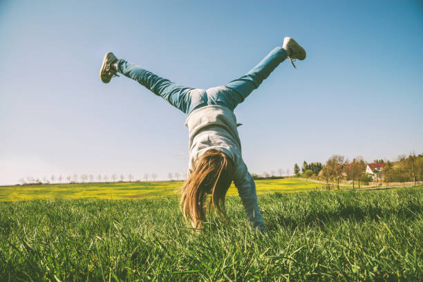 Happy girl playing in handstand on summer meadow
