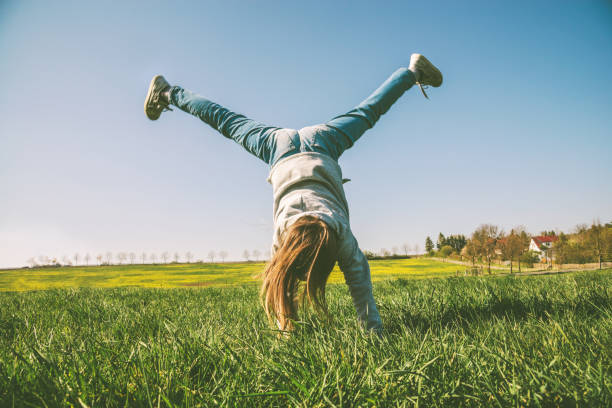 szczęśliwa dziewczyna gra w podpórce na letniej łące - acrobatic activity zdjęcia i obrazy z banku zdjęć