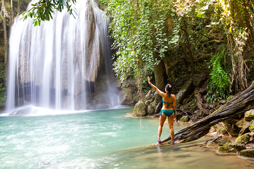 Woman in blue swimsuit stand  at  Erawan Waterfall and natural in Kanchanaburi province Thailand. Erawan Waterfall Is a beautiful and famous water fall