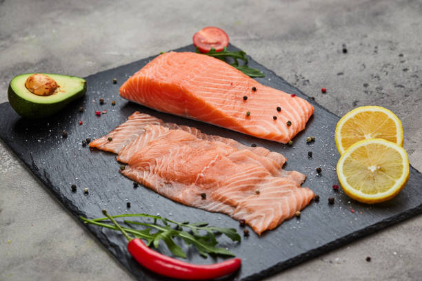 istock Fresh sliced salmon fillet with arugula, avocado and lemon on slate plate. Wild atlantic fish 1220745937