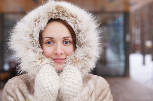Beautiful slim girl in light fur coat in winter park enjoy winter