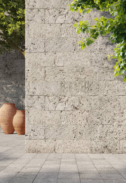 istock Natural stone travertine wall with green leaves, sunlight with shadows. Spring, summer background. 3d rendering. 1220749753