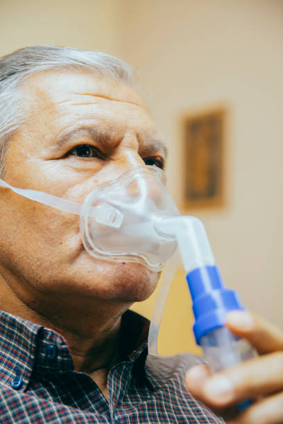 istock Senior man using medical equipment for inhalation with respiratory mask, nebulizer 1220749776