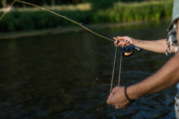 istock Man`s hands holding fly fishing rod 1220750930
