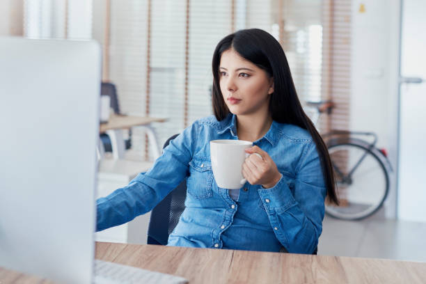 istock Asian woman drinking coffee and working on computer 1220762109