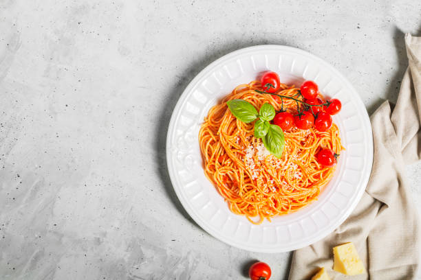 istock Spaghetti with tomato sauce and cherry tomatoes with basil on a concrete white background with copy space 1220762149