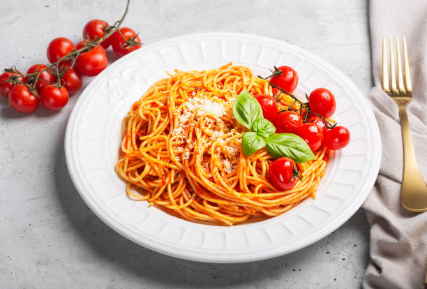 istock Spaghetti with tomato sauce and cherry tomatoes with basil on a white background, close up 1220762177