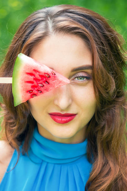 Woman covers eye with watermelon.