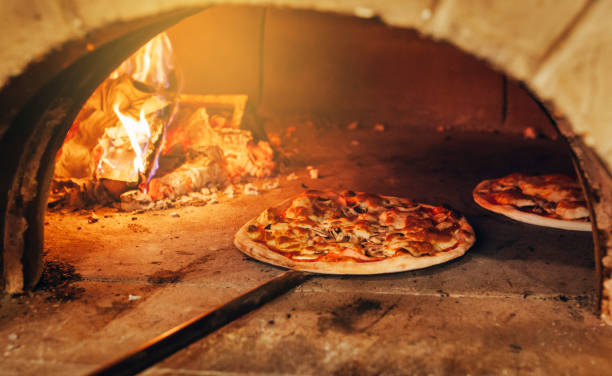 la pizza italiana viene cotta in un forno a legna. - pizzeria foto e immagini stock