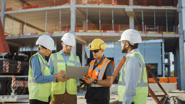 istock Diverse Team of Specialists Use Laptop Computer on Construction Site. Real Estate Building Project with Civil Engineer, Architectural Investor, Businesswoman and Worker Discussing Plan Details 1220768084