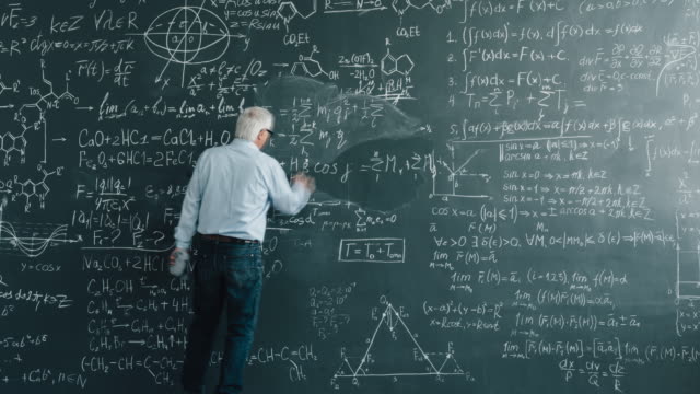 Zoom-in time lapse of senior man scientist writing calculations on blackboard