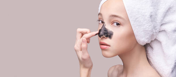 молодая девушка, применяя черную маску для лица - mud wellbeing spa treatment beautician стоковые фото и изображения