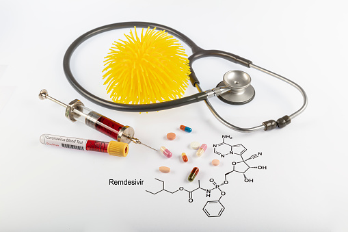 Remdesivir antiviral, thought to could cure Covid-19 respiratory sickness. Remdesivir molecule and some medicines/injection syringe near the coronavirus.