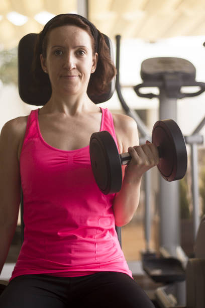 istock Woman doing dumbbells at happy gym 1220773071