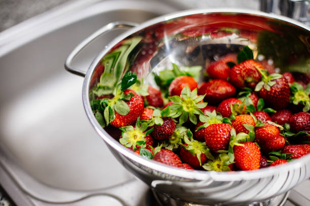 istock Woman washing strawberries 1220774476