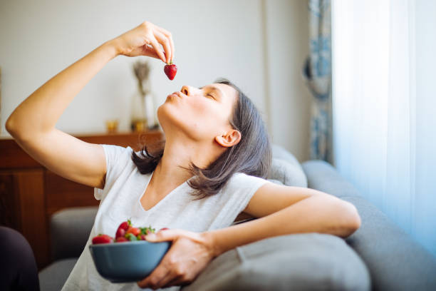 istock Young woman eating strawberries 1220774868