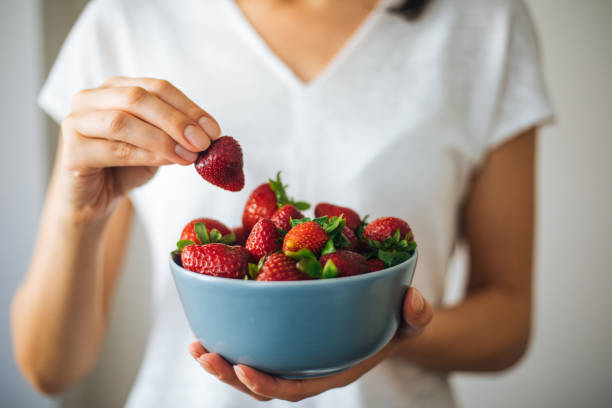 istock Young woman eating strawberries 1220775112