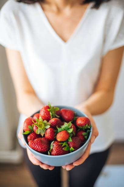 istock Young woman eating strawberries 1220775174