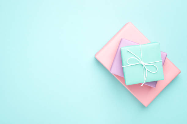 Pastel colored gift boxes. Pastel colored gift boxes on turquoise background. Minimal styled flat lay for Mother's Day, Birthday and Holiday. Books wrapped in gift paper. birthday present photos stock pictures, royalty-free photos & images