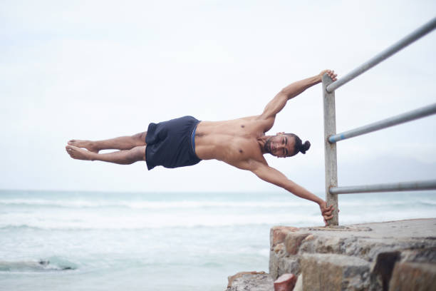 Life is a huge balancing act Full length shot of a handsome and athletic young man exercising outdoors near the beach power balance pavillion stock pictures, royalty-free photos & images