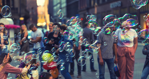 People play with soap bubbles on a square in Riga on a summer sunny day.