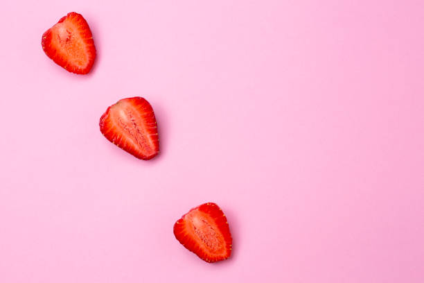 istock Strawberries cut in half, on a pink background in the form of friendly rows 1220780265