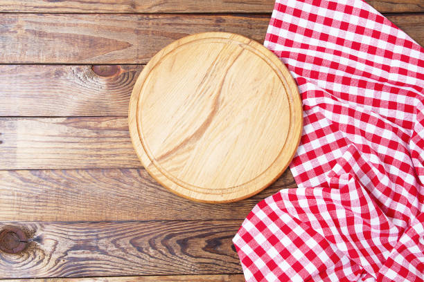 istock Brown old vintage wooden table with framed red checkered tablecloth and pizza cutting board.Thanksgiving day and Cristmas table concept. Top view and copy space. Selective focus 1220782032
