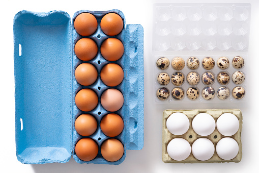 Dozen brown eggs carton and six white eggs and quail eggs isolated on white background