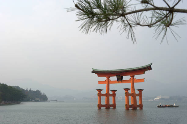 Miyajima Island,Japan - November 08, 2010: Famous Torii Gate belonging to the Itsukushima Shrine, located at the Miyajima Island in the Hiroshima Prefecture. When it is high tide, the gate seems to float on top of the water. A sampan with tourists nearby the gate.