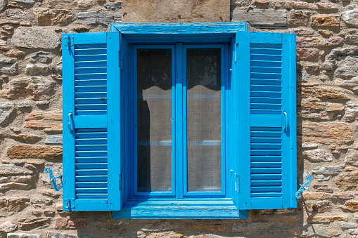 Brown old wooden window with closed shutters, grey house wall with rough surface, no person, vertical format