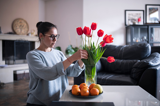 beautiful young woman arranging tulips at home.