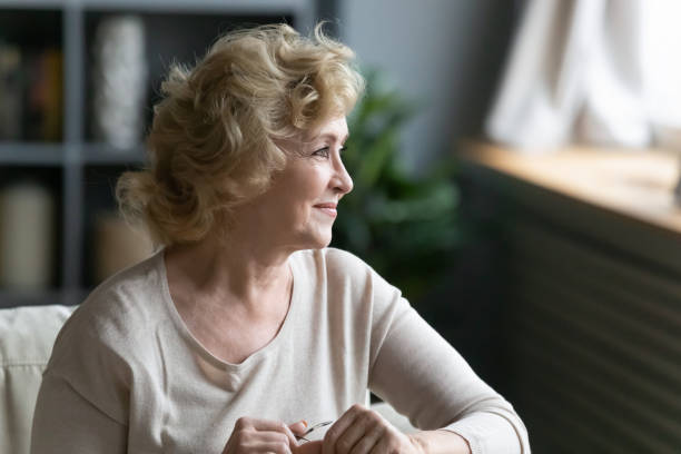 Smiling aged woman sitting on sofa looking out the window
