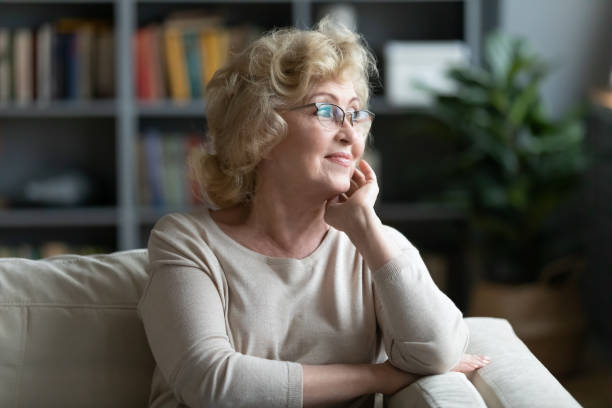 istock Satisfied calm aged woman sitting on couch looking at window 1220790923