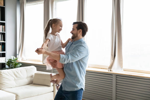 istock Father holds on hands small daughter people dancing at home 1220791036